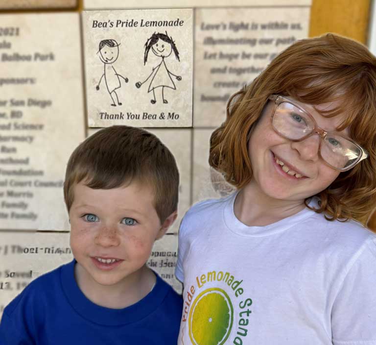 Bea and Mo smiling in front of the Bea's Pride Lemonade thank-you tile